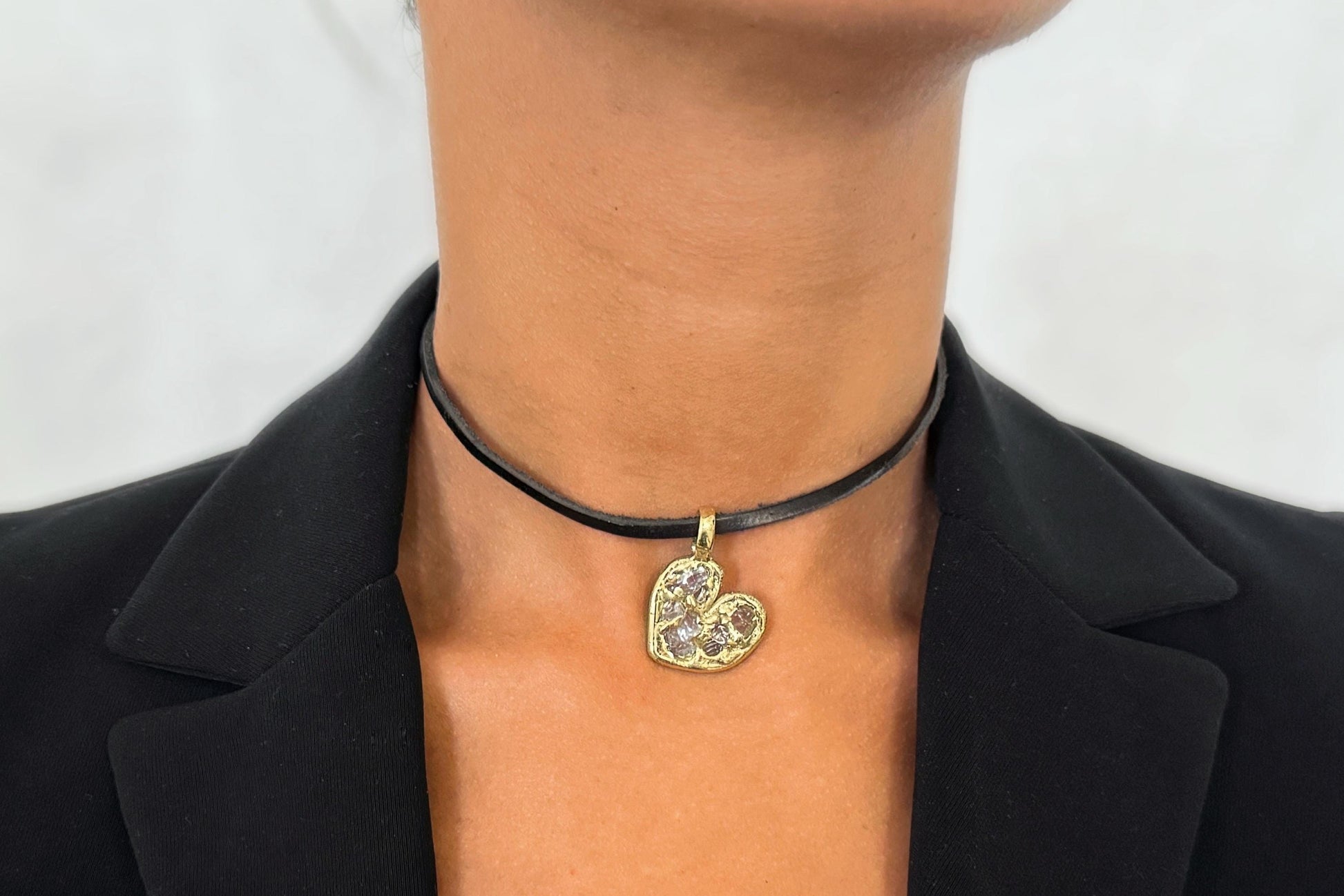 Brass necklace with a heart-shaped pendant worn by a person against a plain background