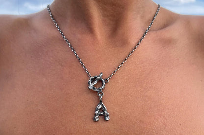 Silver necklace with a unique letter pendant on a person.