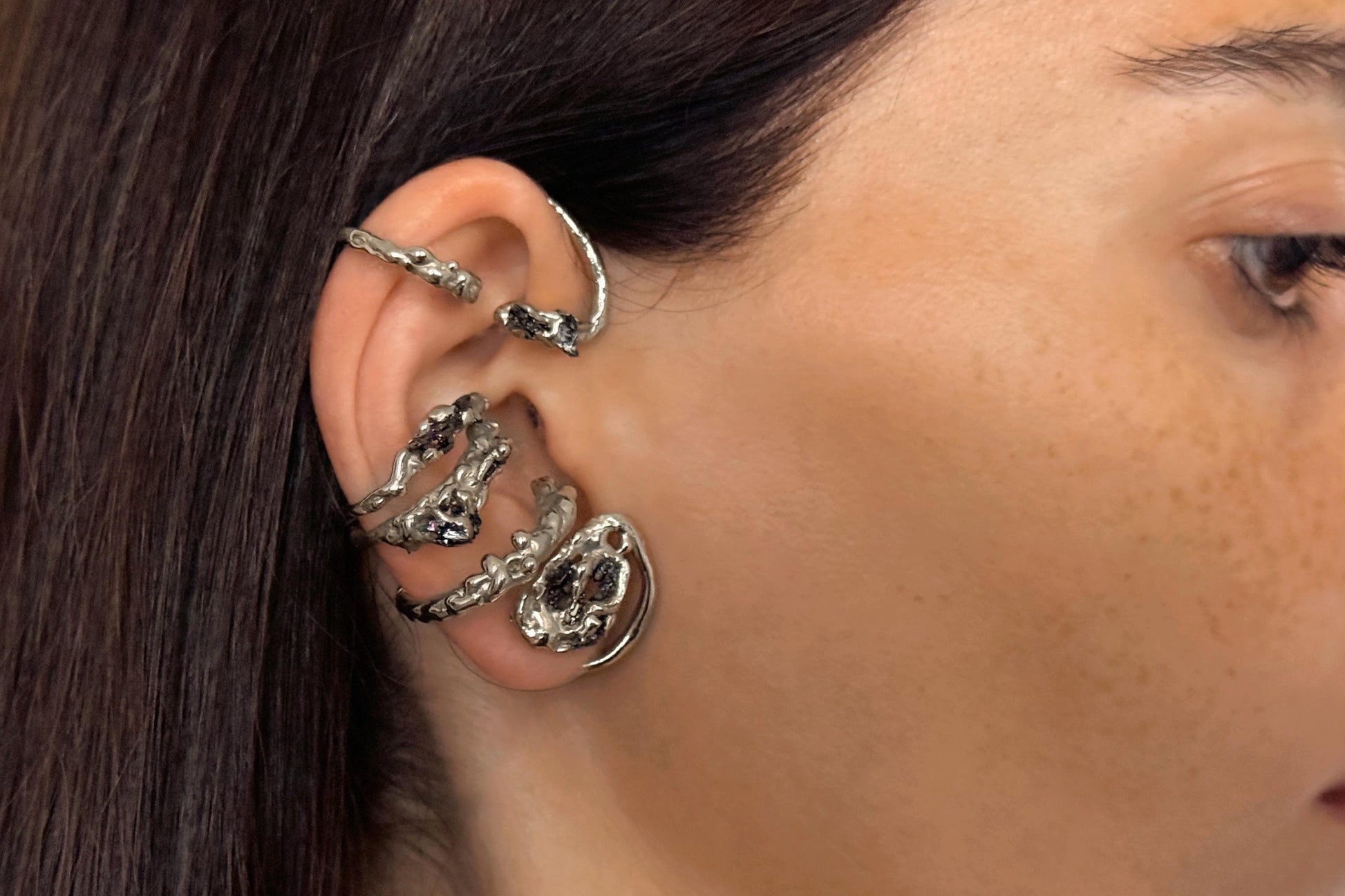 Close-up of a person wearing sterling silver wrap earring with black stones