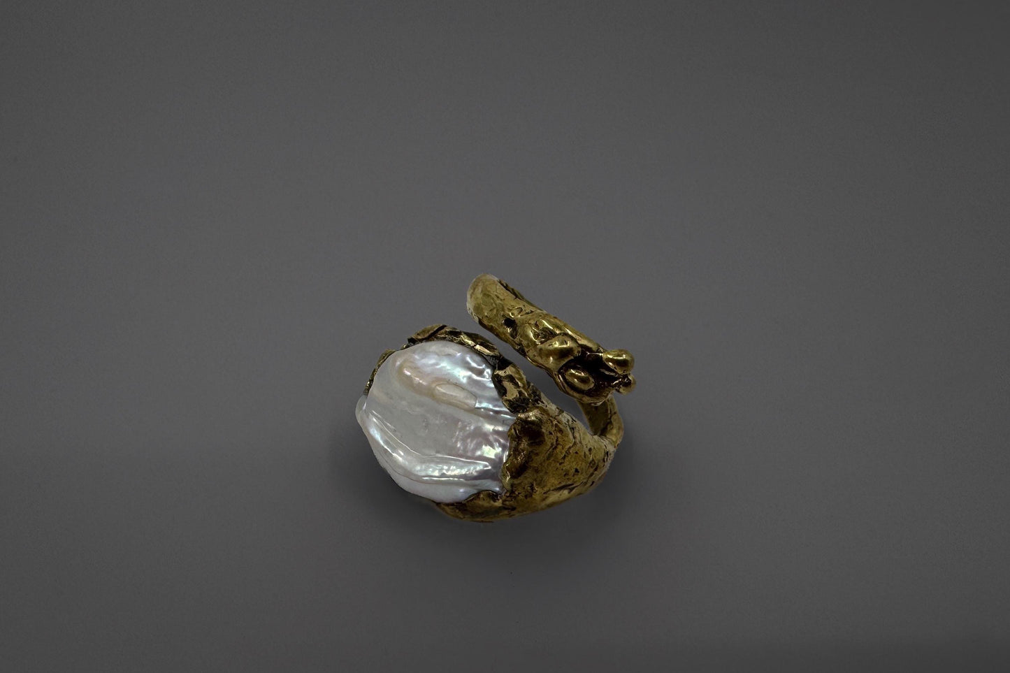 Brass ring with a natural freshwater pearl on a gray background