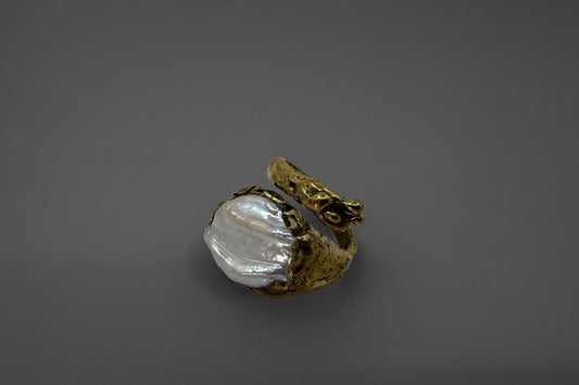 Brass ring with a natural freshwater pearl on a gray background